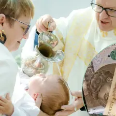 Chrzest dziecka z polskimi banknotami w tle.