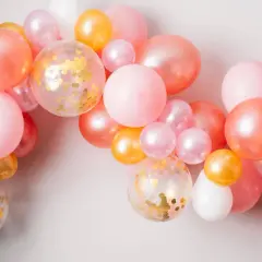 Girlanda z różowych, łososiowych, złotych i białych balonów, w tym kilka z konfetti.